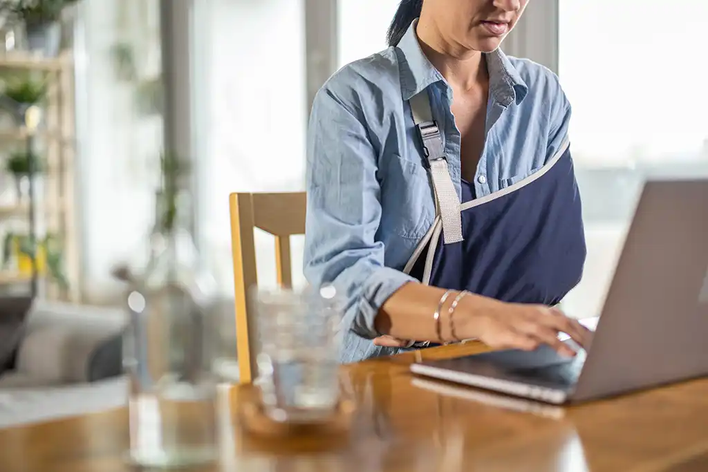 Woman at desk with arm in sling