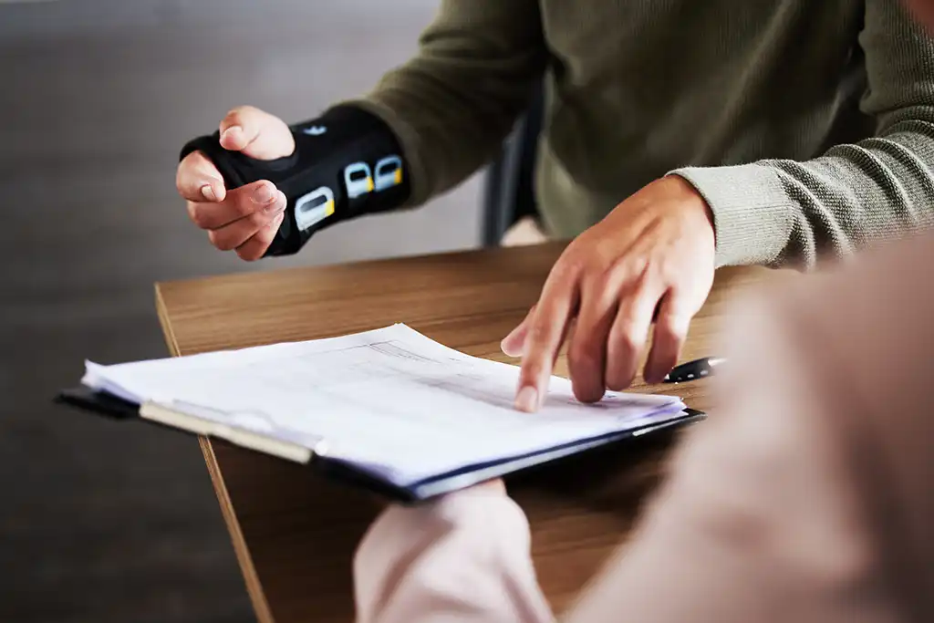 person pointing at paperwork with wrist in a brace
